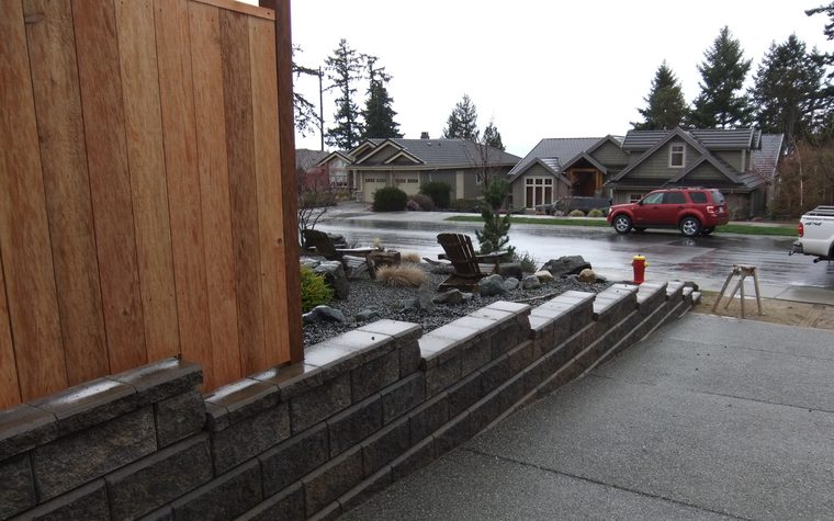 Block retaining wall stepping down beside a driveway