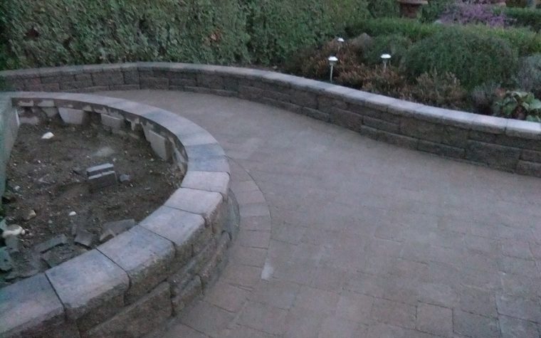 Curved block wall and paving stone path with garden lights