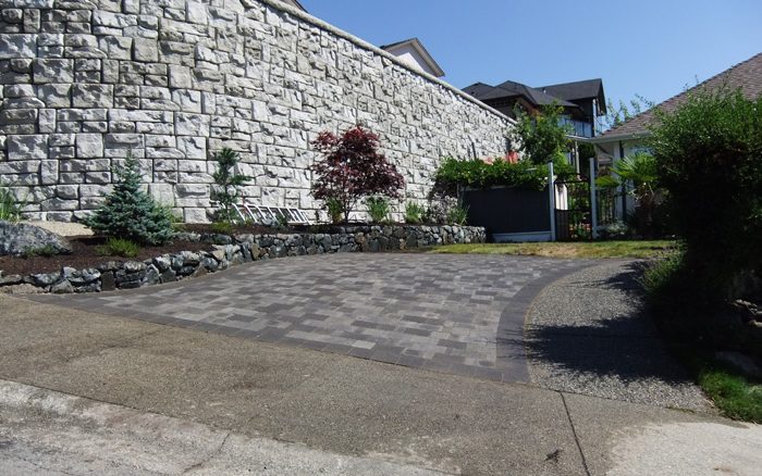 Paving stone driveway below a tall rock wall