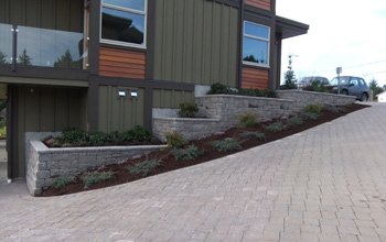 Paving stone driveway with block retaining walls beside a modern home