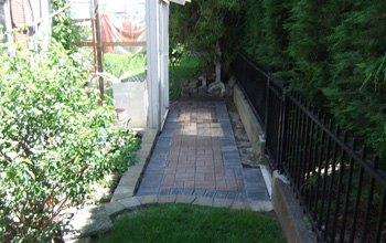 Paving stone walkway beside a black iron fence