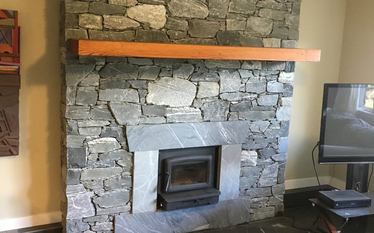 Stone fireplace with a wood mantel and slate hearth